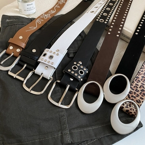 Vue à plat de plusieurs ceintures en cuir avec clous et boucles ovales sur fond denim