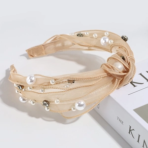 Detail of retro champagne mesh headband with pearls and rhinestones on a white book