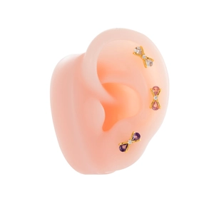 Titanium steel bow stud earrings with sparkling gemstones shown on a silicone ear model