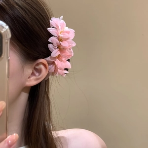 Dettaglio di un accessorio per capelli con fiori di stoffa rosa per un look dolce.