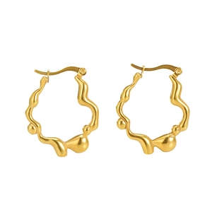 Détail des boucles d'oreilles irrégulières en acier inoxydable doré mat sur fond blanc