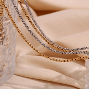 Detailed close-up of 18K gold and silver plated stainless steel box chains on silk