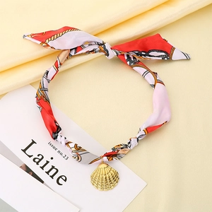 Détail du collier foulard en soie imprimé avec pendentif coquillage doré sur soie