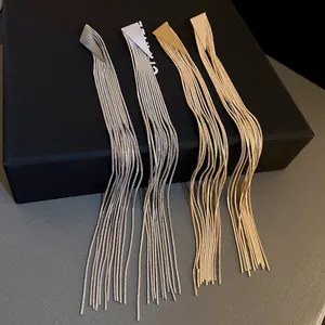 Detail of long metal tassel earrings in gold and silver with geometric triangle studs