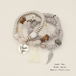Detail of bohemian multilayer beaded bracelet with tassel, wing charm and engraved pendant