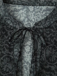Close-up of metallic thread floral print fabric with tie neck collar on a dark blouse