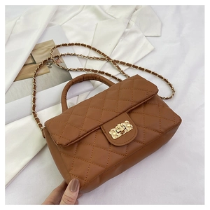 Detailed close-up of brown quilted faux leather handbag with gold chain and square lock