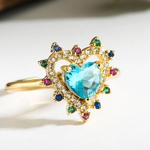 Macro shot of 18K gold heart ring featuring a light blue gemstone with colorful accents