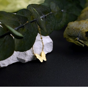 Detailansicht einer 18K Gold Schmetterlingshalskette auf einem weißen Mineralstein