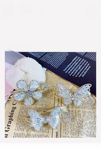 Detail view showing sparkling butterfly and flower zirconia hair claws with gold finish