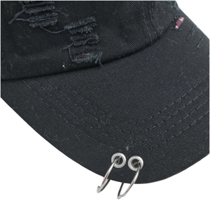 Detailansicht der schwarzen Baseballkappe mit Distressed-Effekt und zwei silbernen Metallringen
