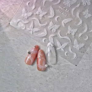 Détail macro de stickers ongles 3D gaufrés blancs avec papillons et motifs de lune