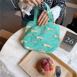 Green canvas lunch bag with swimmer prints in a stylish cafe lifestyle setting