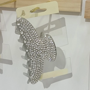 Detailed view of silver hair claw clip encrusted with sparkling rhinestones on wood