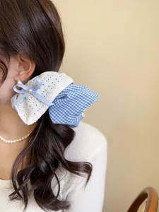 Detailed close-up of blue plaid and lace bow scrunchie with pearl on wavy hair