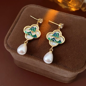 Détail de boucles d'oreilles trèfle doré avec émail vert et perle poire sur velours