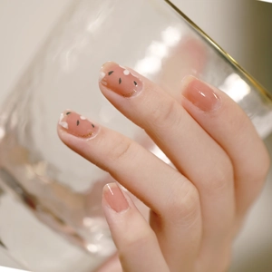 Pink heart press-on nails with green leaf patterns and gold glitter accents