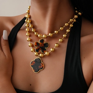 Detail of double-layer gold beaded necklace featuring leopard print flower pendants on a model