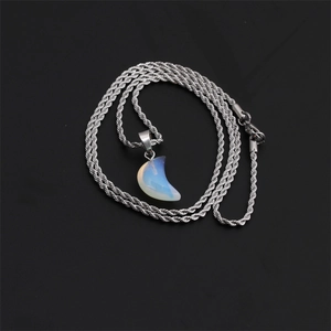 Macro detail of moon-shaped opal pendant with silver twist chain on black background
