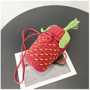 Detail of a handmade strawberry woven shoulder bag with vivid red texture and green leaf top