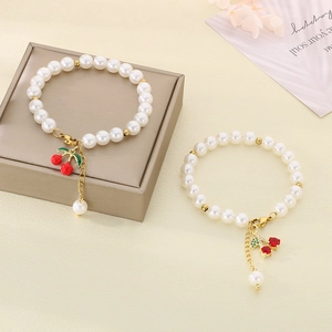 Beaded pearl bracelet featuring elegant red cherry charms with sparkling crystal accents