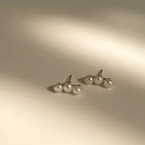 Minimalist triple pearl stud earrings with three white pearls on a gold metal base