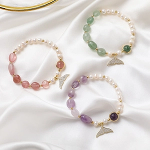 Detailed view of freshwater pearl bracelets with whale tail charms and colorful gemstones