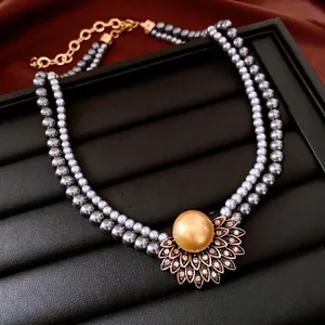 Collier double rang de perles grises avec pendentif floral doré sur soie sombre
