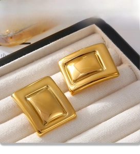 Détail de boucles d'oreilles rectangulaires dorées avec placage PVD dans un écrin à bijoux