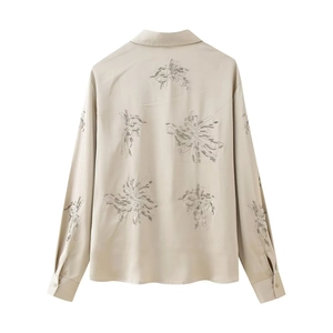 Detail of floral embroidery and satin fabric on the back of a beaded champagne shirt