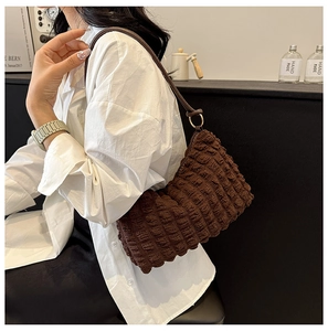 Brown bubble texture hobo bag worn by model showing side view and capacity in a cafe