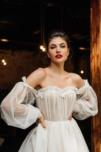 Dettaglio dell'abito da sposa a spalle scoperte con maniche in tulle e pizzo floreale