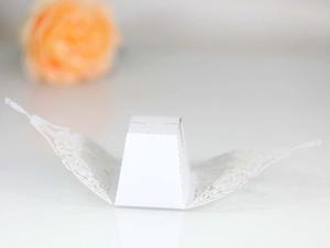 Detailed laser-cut hollow pattern on white paper wedding favor box with floral design