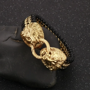 Detailed view of golden double lion heads on black braided leather punk style bracelet