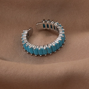 Macro detail of silver adjustable ring with turquoise zircon stones on brown fabric