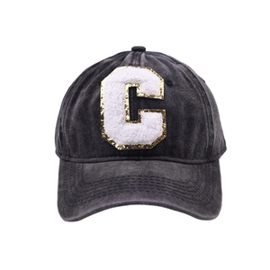 Dettaglio della lettera C in ciniglia con paillettes dorate su cappellino in cotone