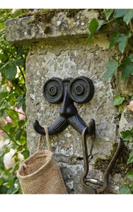 Detalle de un gancho de pared vintage de hierro fundido con forma de bigote en piedra