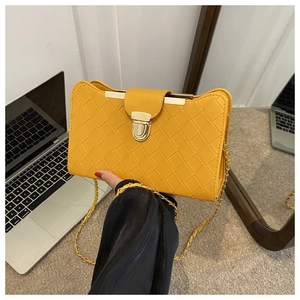 Detail of yellow woven faux leather bag with vintage gold metal buckle and chain strap