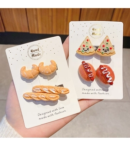Close-up of realistic pizza and hot dog resin hair clips on a white display card