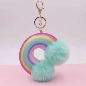 Close-up of rainbow leather keychain with turquoise plush pom poms and golden metal clasp