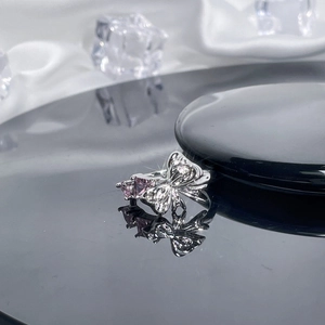 Detailed macro view of silver bow ring with pink triangle gemstone and micro-pave crystals