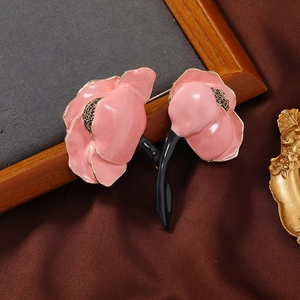 Macro detail of pink enamel peony brooch with gold edges on elegant dark stone