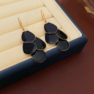 Detail showing multi-layer black petal fringe earrings in a premium jewelry display case