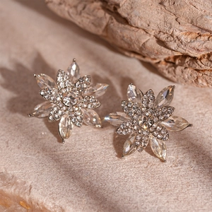 Macro shot of silver layered snowflake earrings with crystals on a textured rock base