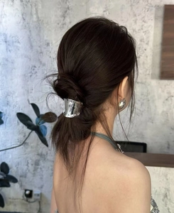 Close-up of minimalist silver metal hair clip and matching circular earrings on model