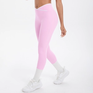 Détail de la taille haute croisée en V sur un legging de yoga rose avec liseré blanc
