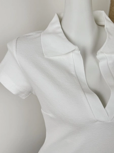 Close-up of white short sleeve polo shirt featuring a ribbed texture and deep V-neck design