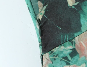 Dettaglio macro della cerniera invisibile su abito estivo in raso verde con rose