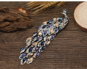 Close-up of vintage peacock brooch with colorful rhinestones and long tassel on wood