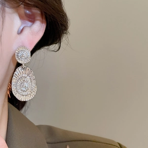 Detailed view of silver textured double oval earrings worn on model's ear for style